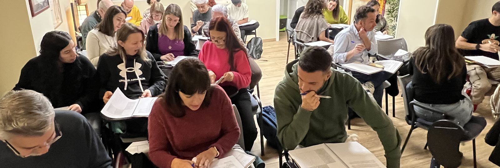 Alumnos siguiendo una clase presencial de Acupuntura Distal con el material del curso sobre la mesa